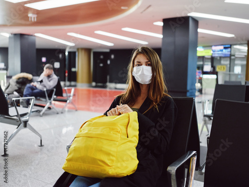 woman passenger wearing medical mask at airport waiting yellow backpack