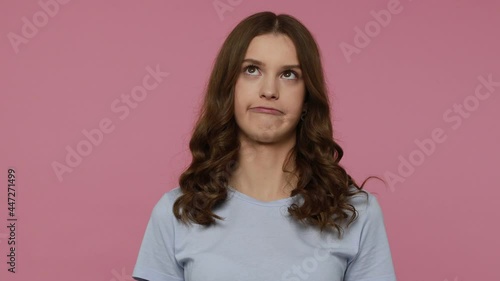 Carefree funny comical young female making humorous face with eyes crossed, playing fool, having fun with stupid brainless expression. Indoor studio shot isolated over pink background. photo