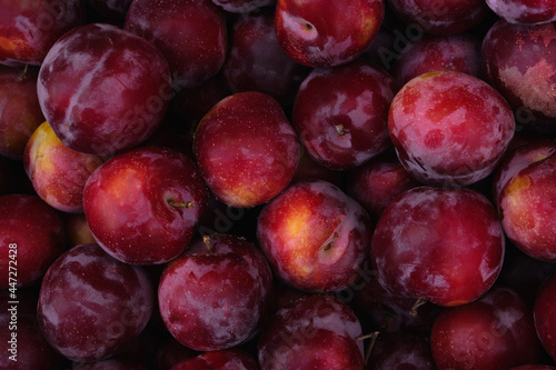 Plums background. Ripe organic fruits on the market, colorful food texture. Top view, flat lay