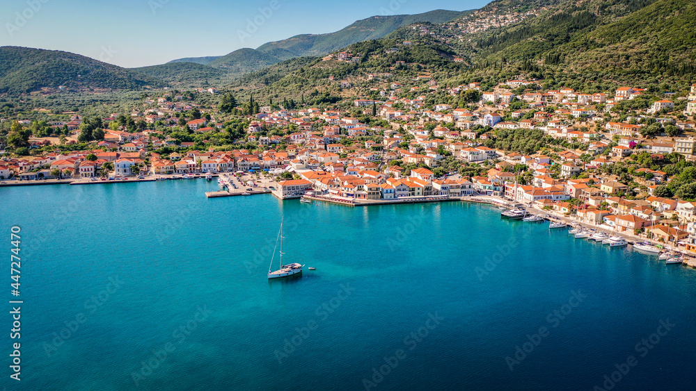 Aerial view of the capital town and the port of Vathy in Ithaca with a sailing boat moored in the middle