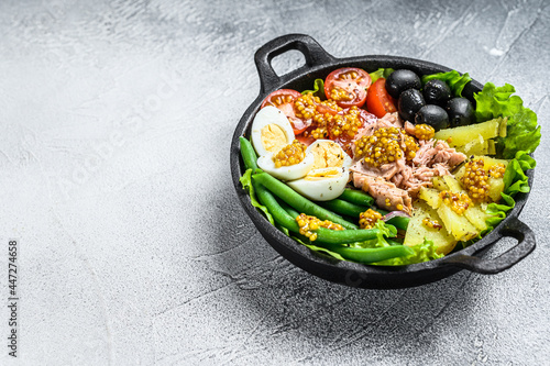 Gourmet nicoise salad with vegetables, eggs, tuna and anchovies in a pan. White background. top view. Copy space