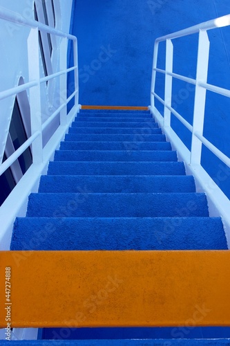 Cruise ship stairs with blue and orange steps going down. Selective focus