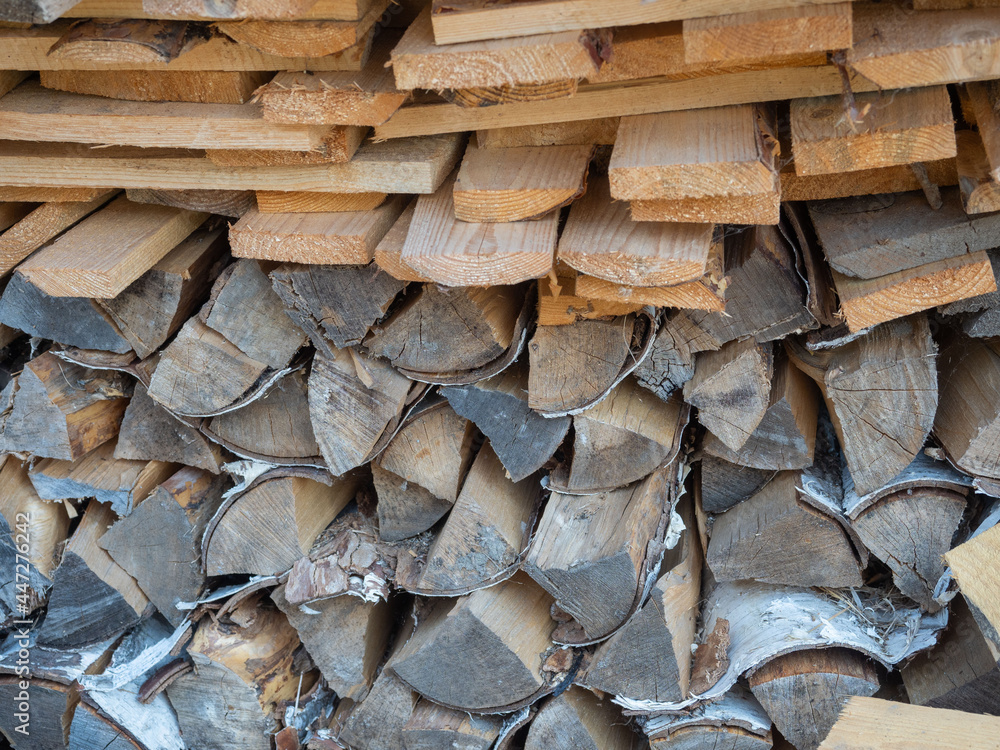 Firewood from boards and birch logs stacked in a woodpile Firewood from boards and birch logs stacked in a woodpile
