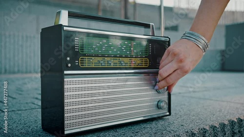 Close up shot of female hand turning on and tuning retro radio receiver, women start riding on roller skates