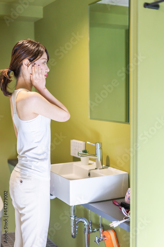 洗面台で顔を洗う若い女性