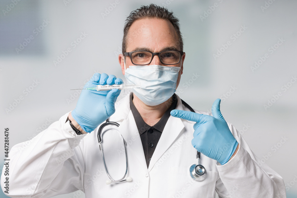 doctor with medical face mask and medical gloves presenting a syringe pulled up with a coronavirus vaccine doctor with medical face mask and medical gloves presenting a syringe pulled up with a coronavirus vaccine