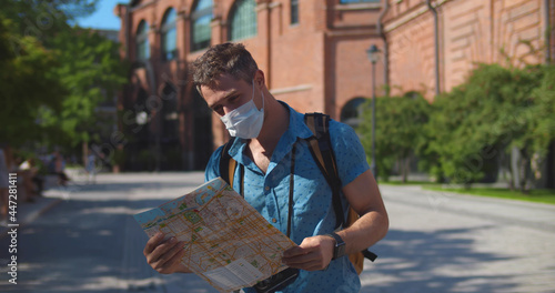 Young caucasian tourist man in safety mask looking for directions on map