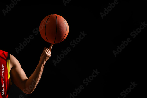 Basketball player spinning ball on black background, closeup. Space for text © New Africa