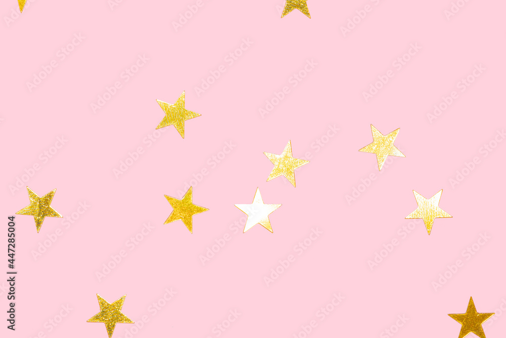 golden metallic star confetti on a pastel pink background