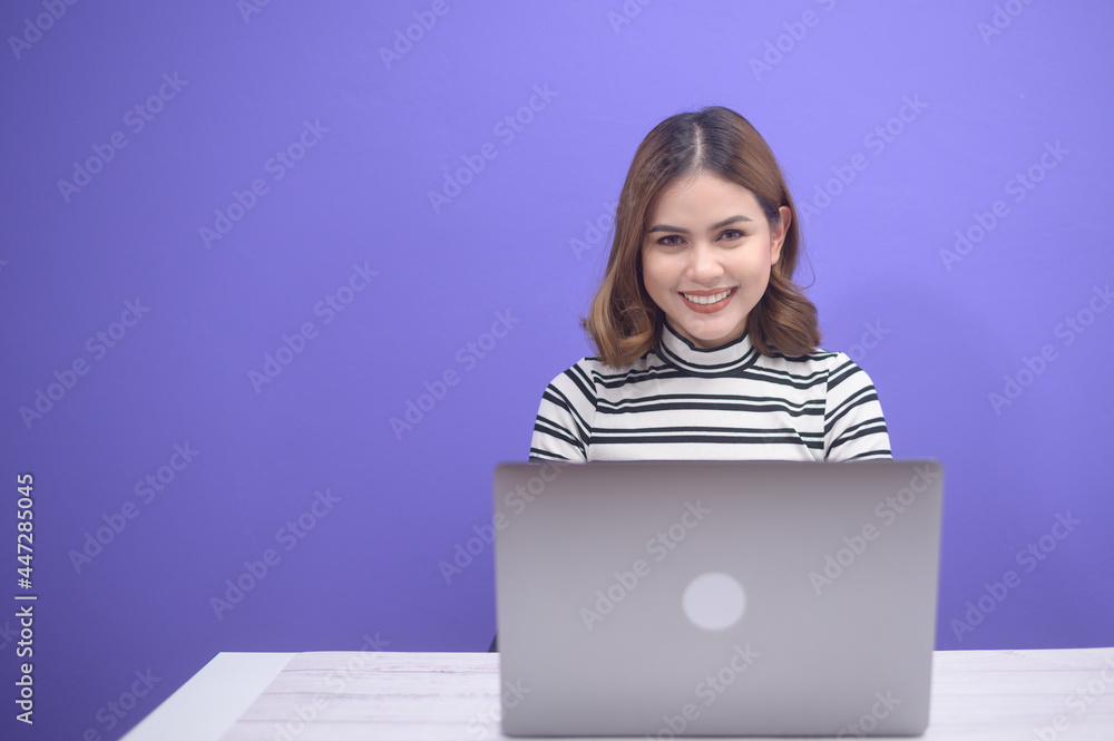 Young beautiful woman is working with her computer over blue background.. Young beautiful woman is working with her computer over blue background..