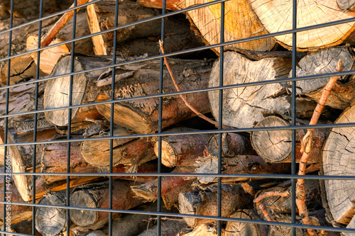 Firewood behind an iron black grate. Place of storage of firewood