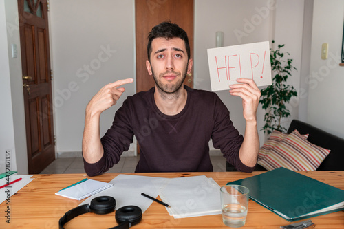 Stressed person working from home and holding a sign asking for help "help!"
