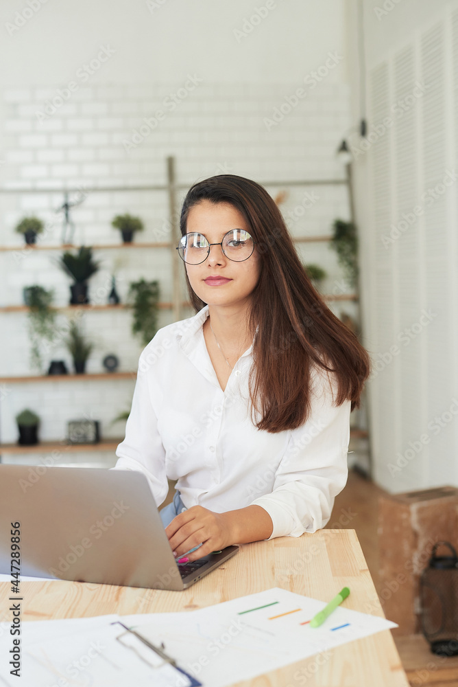 Thoughtful young woman in smart casual wear working while sitting in the office. Portrait of a young woman working at a laptop. Small business and business Thoughtful young woman in smart casual wear working while sitting in the office. Portrait of a young woman working at a laptop. Small business and business