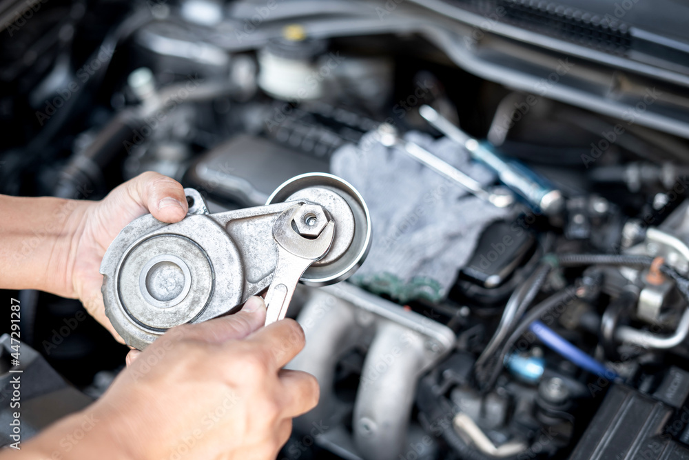 Wrench in the hand of a technician for take off Belt Tension Pulley old part car engine Replacement of spare parts in engine room Wrench in the hand of a technician for take off Belt Tension Pulley old part car engine Replacement of spare parts in engine room