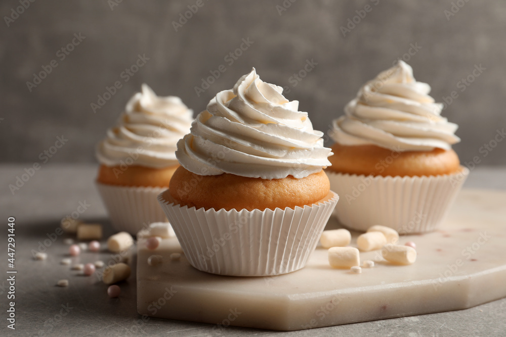 Delicious cupcakes decorated with cream on light grey table
