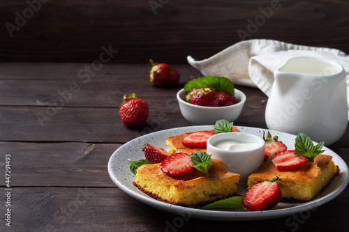 Cottage cheese casserole with strawberries and mint. Delicious homemade dessert made of curd and fresh berries with cream. dark wooden background, copy space.