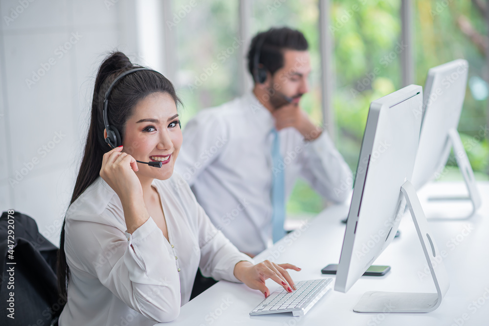 young asian woman working receiving call wear headphone consulting or solving problems for customers,Employees wearing headphones doing telemarketing,man blurr background young asian woman working receiving call wear headphone consulting or solving problems for customers,Employees wearing headphones doing telemarketing,man blurr background