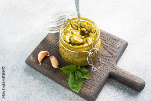 Pesto sauce in a glass jar, fresh basil leaves and garlic. copy space
