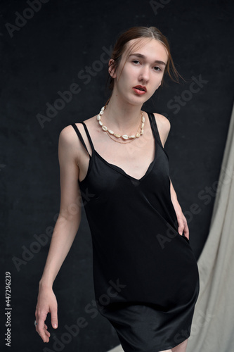 Vertical photo of caucasian young girl model posing at camera on black background