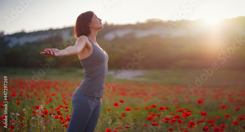 Young beautiful woman with raised arms in spring field