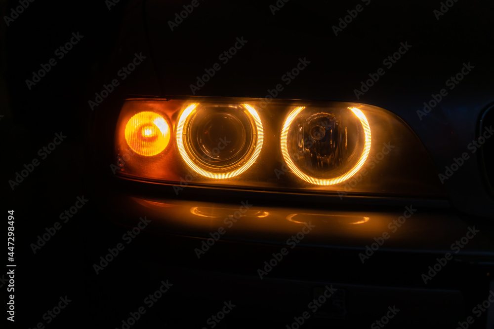 Close-up of orange car headlights in the dark, at night Close-up of orange car headlights in the dark, at night