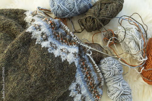 Icelandic wool knitted lopapeysa sweater in progress with yarn balls and needles photo