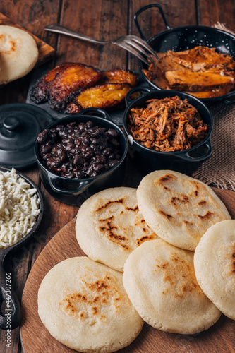 Table served with Venezuelan breakfast, arepas with different types of fillings such as caraotas, carne mechada, pernil , fried plantain and cheese