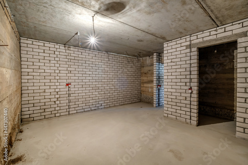 Empty unfurnished basement room with minimal preparatory repairs. interior with white brick walls © hiv360