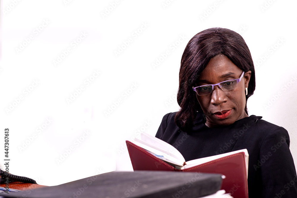 Serious mature businesswoman reading a notebook in the office. Serious mature businesswoman reading a notebook in the office.
