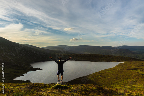 Man raising his arms admiring the lough ouler in the Wicklow Mountains Ireland photo