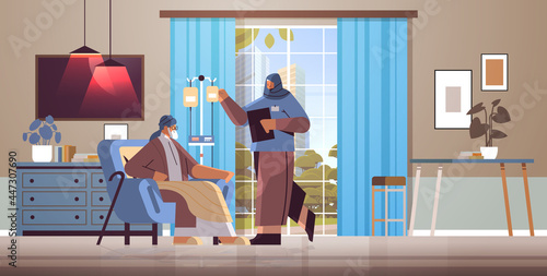 friendly arab nurse or volunteer checking dripper of elderly man patient home care services healthcare