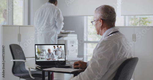 Mature male doctor having video conference with colleague sitting in clinic office