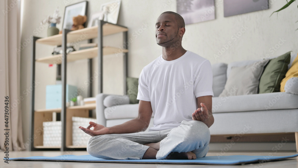 African Man Meditating on Yoga Mat at Home