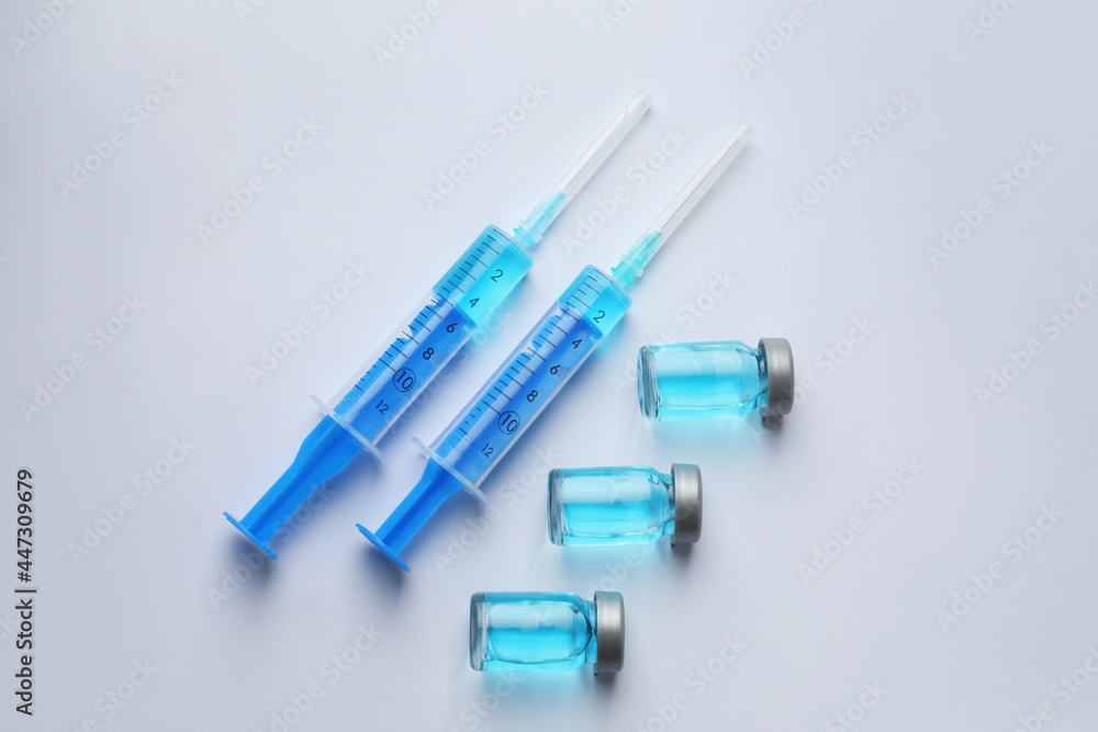 Disposable syringes with needles and vials on white background, top view Disposable syringes with needles and vials on white background, top view