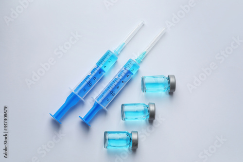 Disposable syringes with needles and vials on white background, top view
