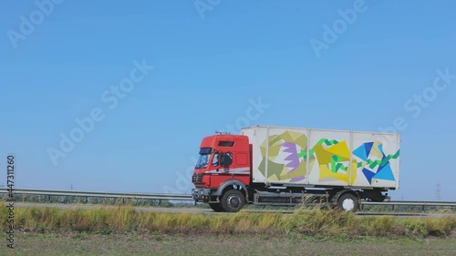 Wallpaper Mural A truck with a red cab drives along the highway. The truck is driving along the road. Delivery of goods by truck Torontodigital.ca