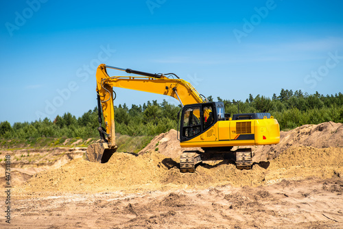 An industrial yellow excavator develops in a sandpit quarry. Industry  technology  mining. Heavy industrial machinery.