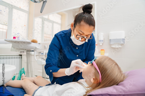the dentist examines the mouth of a kid girl. 