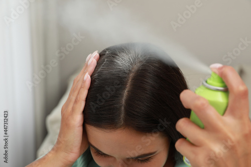 Fényképezés Woman applying dry shampoo onto her hair, closeup