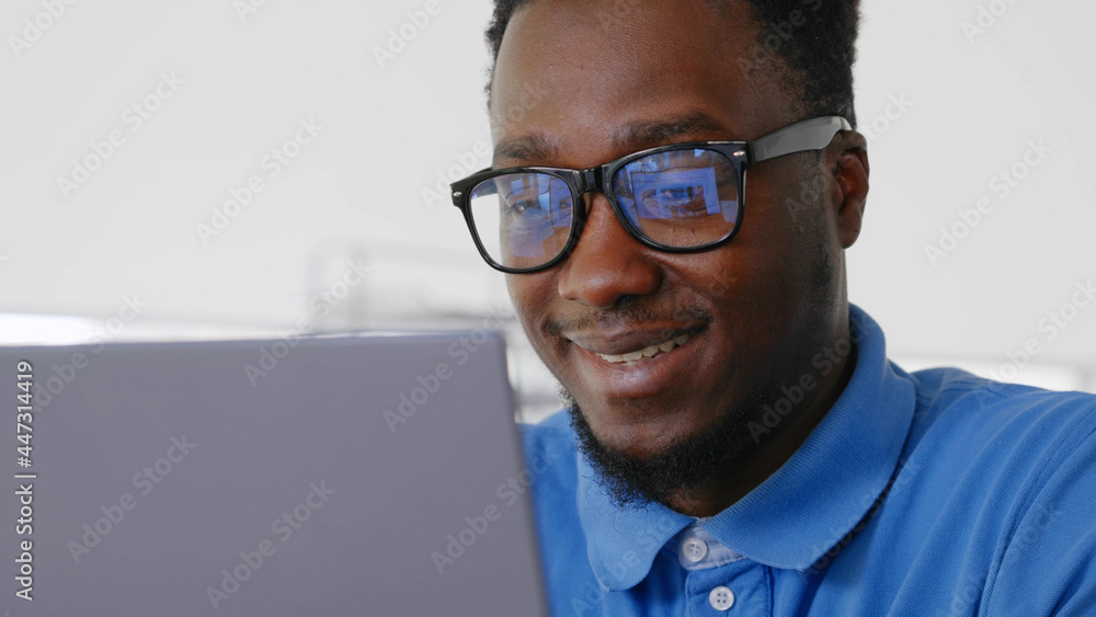 Young positive afro businessman working at desk in office with laptop. Young positive afro businessman working at desk in office with laptop.