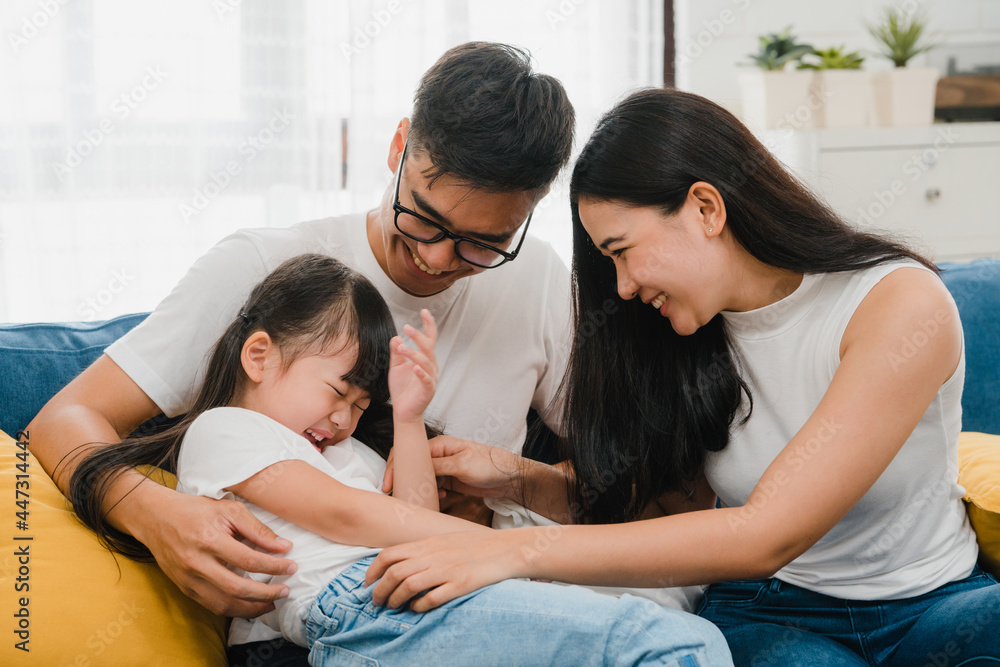 Happy cheerful Asian family dad, mom and daughter having fun cuddling playing on sofa while birthday at house. Self-isolation, stay at home, social distancing, quarantine for coronavirus prevention. Happy cheerful Asian family dad, mom and daughter having fun cuddling playing on sofa while birthday at house. Self-isolation, stay at home, social distancing, quarantine for coronavirus prevention.