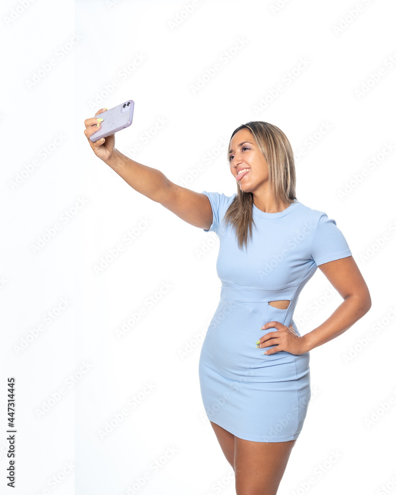 Expresiones de mujer rubia con vestido azul de punto sobre fondo blanco, hablando por el móvil y haciéndose un selfie Expresiones de mujer rubia con vestido azul de punto sobre fondo blanco, hablando por el móvil y haciéndose un selfie