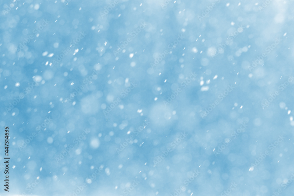 Abstract Christmas background with snowflakes during snowfall on blurred background