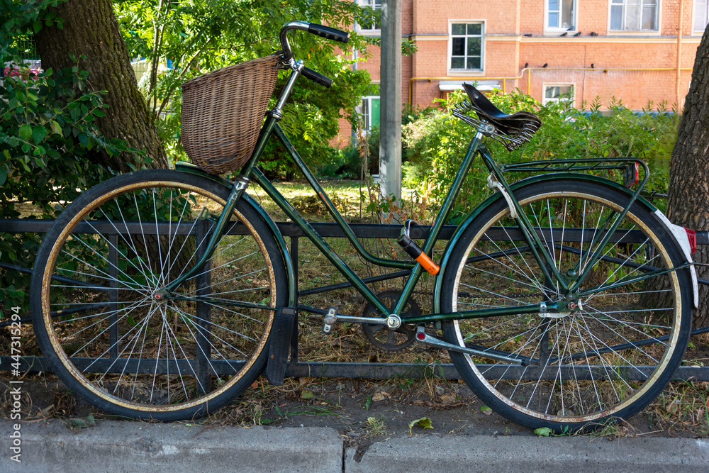 stylish green vintage retro bike with wicker basket parked in the city