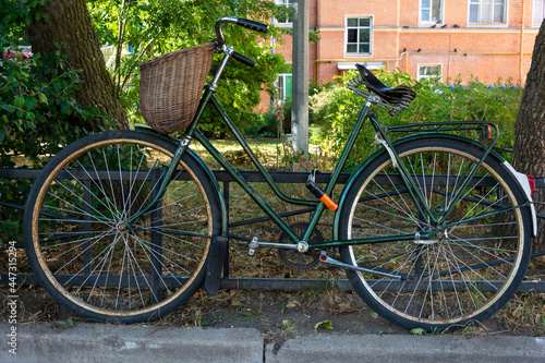 stylish green vintage retro bike with wicker basket parked in the city © Андрей Знаменский