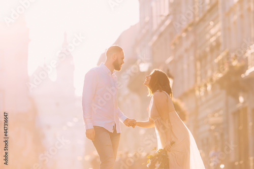 the joy of elegant newlyweds, hand in hand, smiles at each other on a morning walk in the city