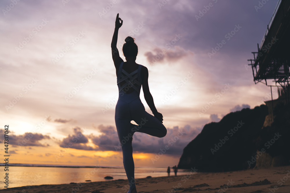 Slim woman standing in yoga pose on beach