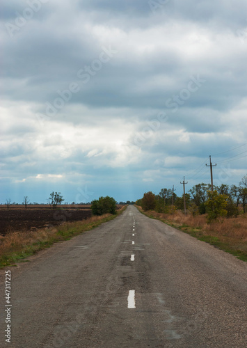 The road runs through the countryside and abuts the horizon.