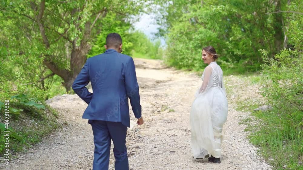 cheerful and happy newlyweds walk along a mountain path among the trees. cheerful and happy newlyweds walk along a mountain path among the trees.