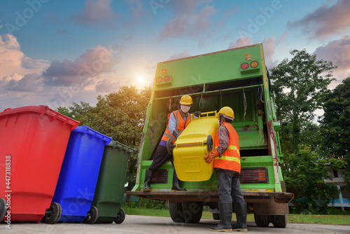 Bild auf Leinwand garbage collector Two garbagemen working together on emptying dustbins for trash removal with truck loading waste and trash bin